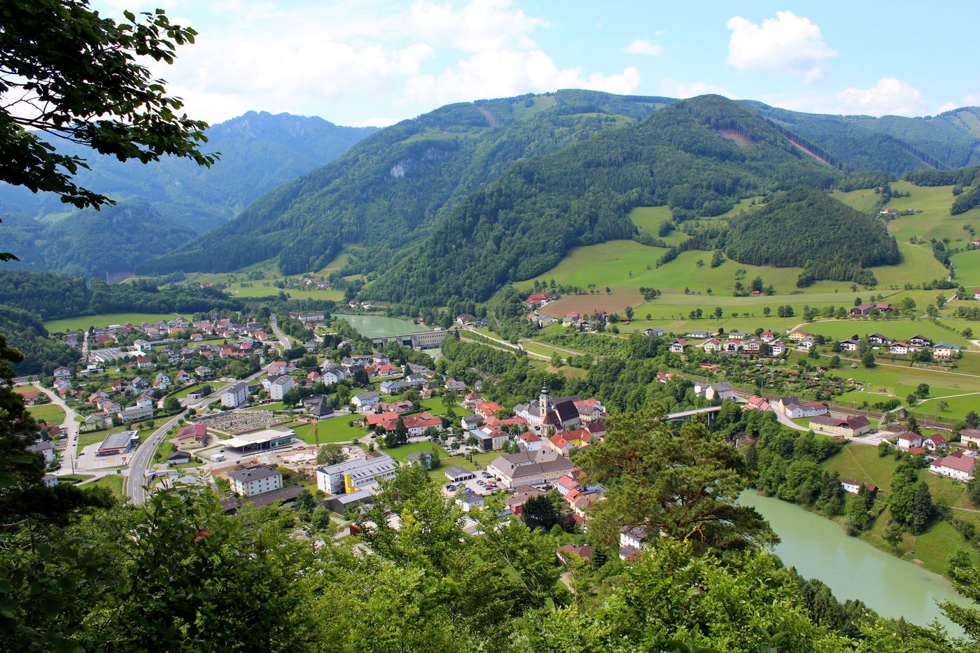 Ort an der Enns mit Wiesen und bewaldeten Bergen im Ennstal
